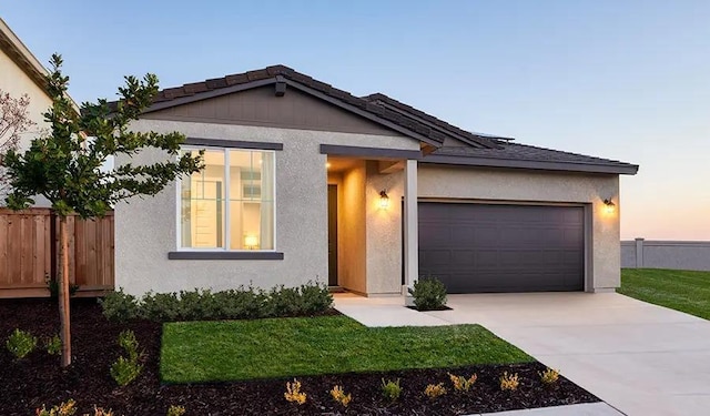 ranch-style house featuring an attached garage, fence, and stucco siding
