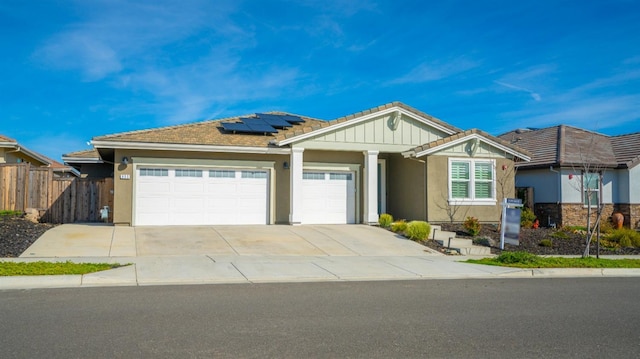 ranch-style home with fence, an attached garage, stucco siding, concrete driveway, and roof mounted solar panels