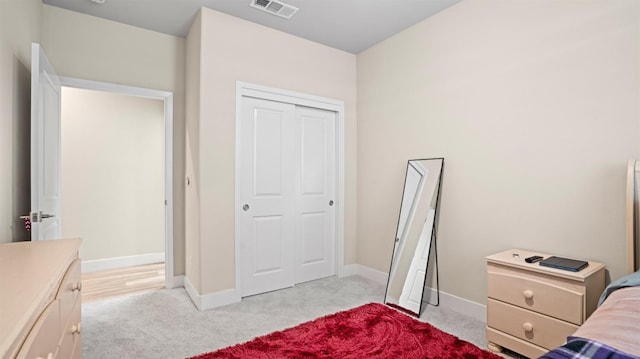 bedroom featuring light colored carpet, a closet, visible vents, and baseboards