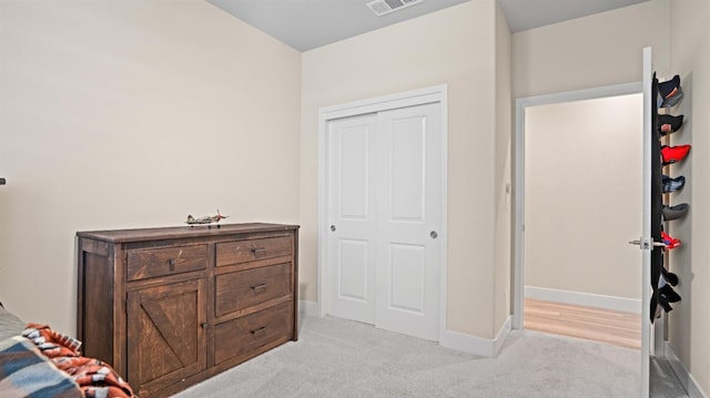 bedroom with light carpet, visible vents, baseboards, and a closet