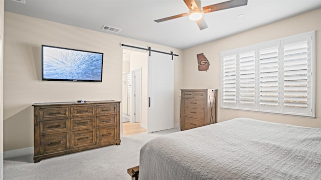 carpeted bedroom featuring a barn door, visible vents, ceiling fan, and baseboards