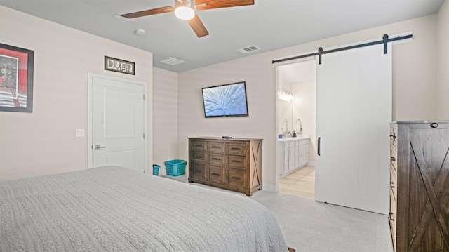 bedroom with carpet, visible vents, a barn door, ceiling fan, and ensuite bath