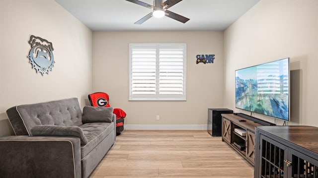 living area with a ceiling fan, light wood-style flooring, and baseboards