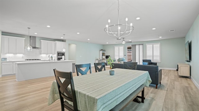 dining area featuring recessed lighting, light wood-style flooring, and an inviting chandelier