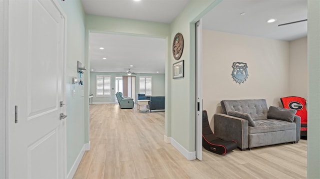 hallway with baseboards, recessed lighting, and light wood-style floors