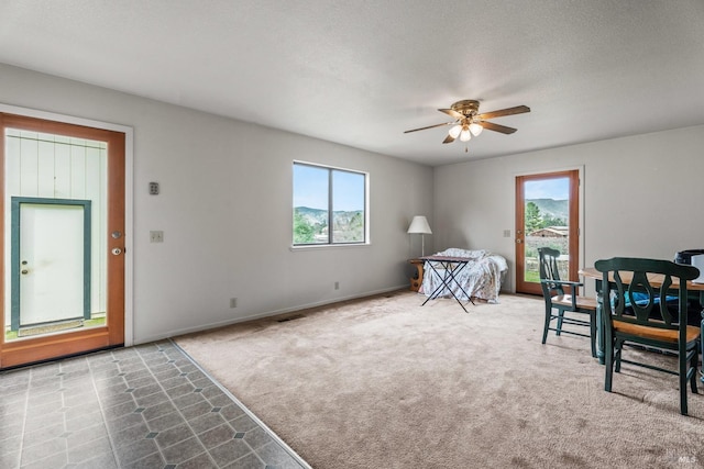 carpeted bedroom with ceiling fan, multiple windows, and a textured ceiling