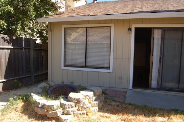 doorway to property featuring roof with shingles, fence, and a chimney