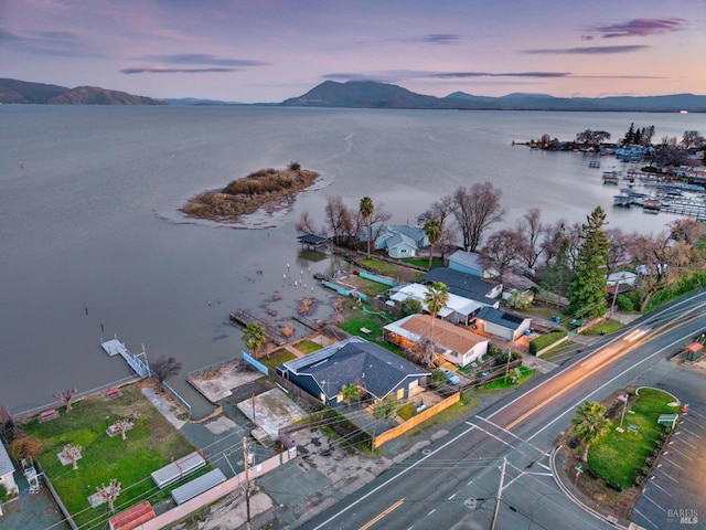 aerial view at dusk featuring a water and mountain view