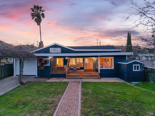 back house at dusk featuring a yard, a porch, and a garage