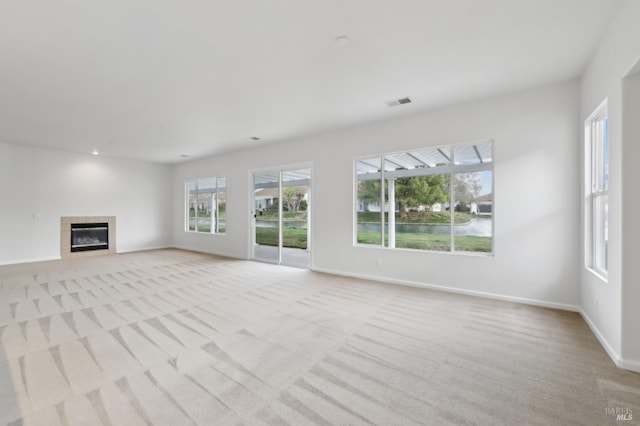 unfurnished living room featuring a tile fireplace and light colored carpet