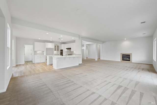unfurnished living room featuring light carpet and a tiled fireplace