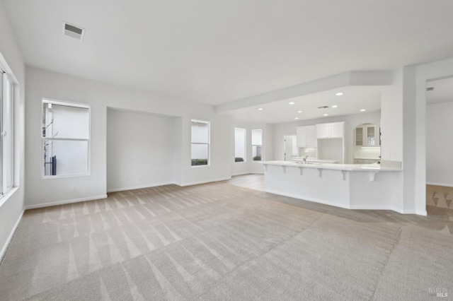 unfurnished living room with sink and light colored carpet