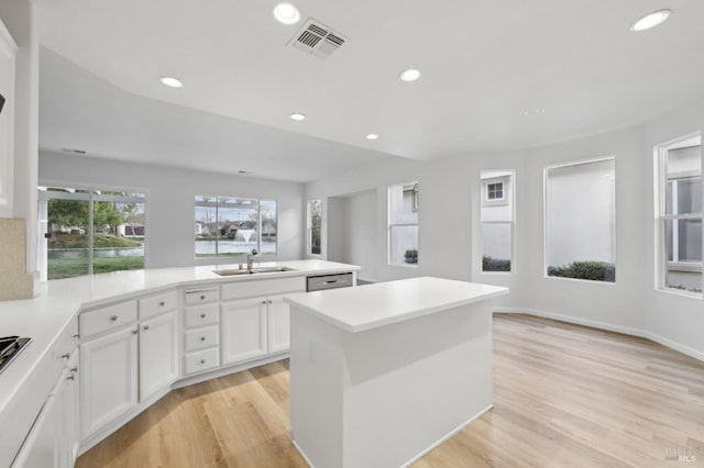 kitchen with sink, a kitchen island, white cabinetry, and light wood-type flooring