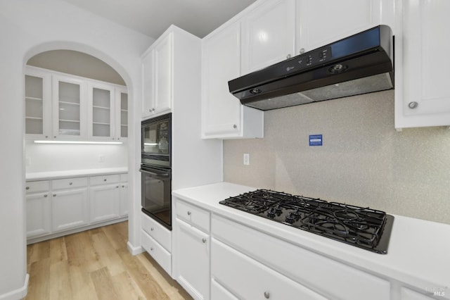 kitchen featuring white cabinetry, black appliances, tasteful backsplash, and light hardwood / wood-style flooring