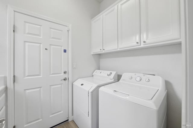 laundry area with washing machine and dryer, cabinets, and light hardwood / wood-style floors