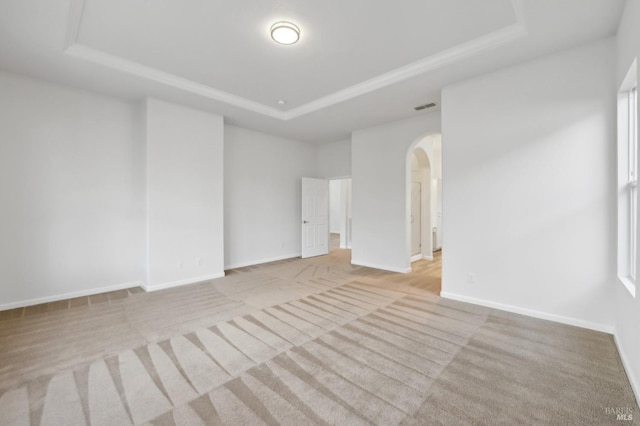 carpeted empty room featuring a tray ceiling