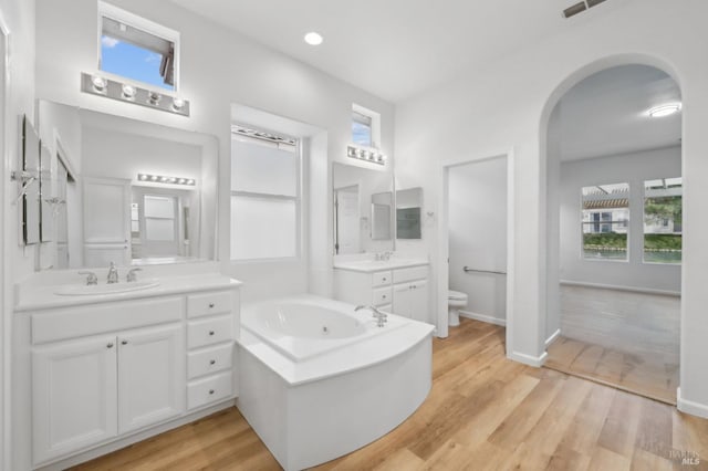 bathroom featuring a tub, a wealth of natural light, wood-type flooring, and toilet