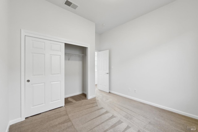 unfurnished bedroom featuring a closet and light colored carpet