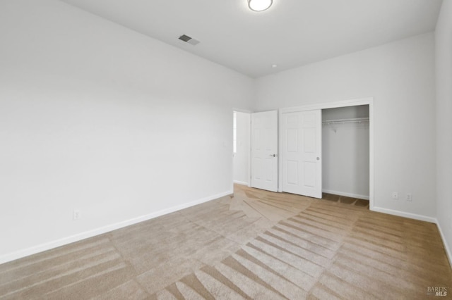 unfurnished bedroom with light carpet and a closet