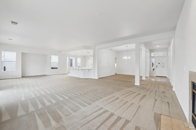 unfurnished living room featuring a chandelier and light carpet