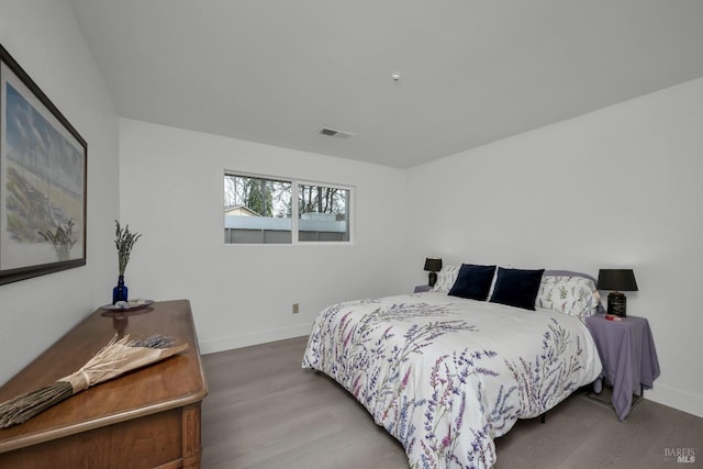 bedroom with wood finished floors, visible vents, and baseboards