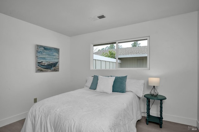 bedroom featuring wood finished floors, visible vents, and baseboards