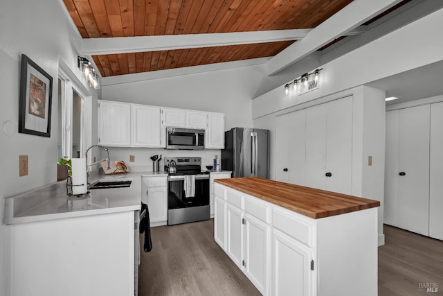 kitchen with vaulted ceiling with beams, butcher block counters, wood ceiling, stainless steel appliances, and a sink