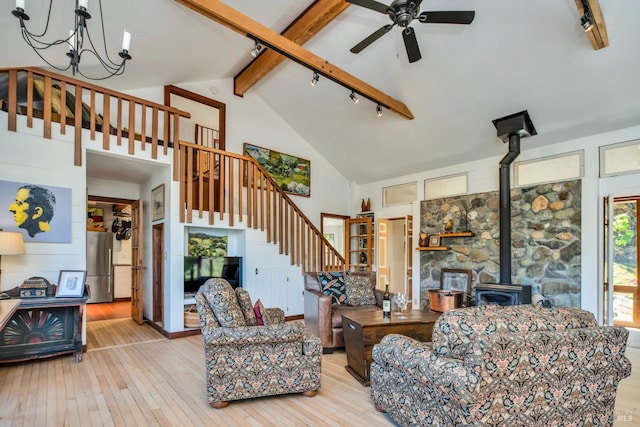 living area featuring beamed ceiling, high vaulted ceiling, stairs, light wood-style floors, and a wood stove