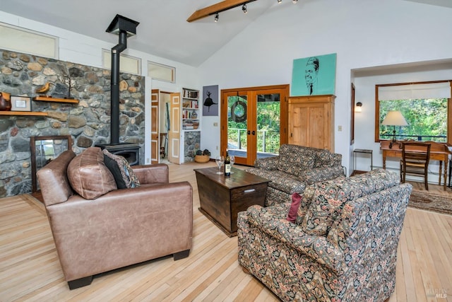 living area with hardwood / wood-style flooring, a wood stove, french doors, and high vaulted ceiling