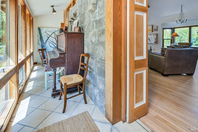 hall featuring light wood-type flooring, an inviting chandelier, and vaulted ceiling