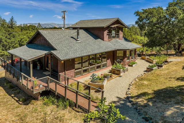 back of house featuring a garden and a shingled roof