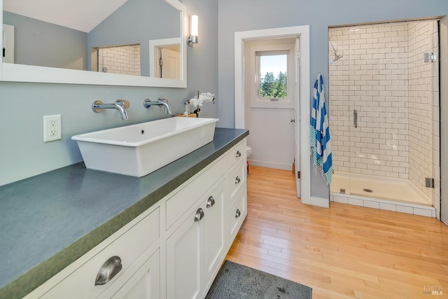 bathroom featuring toilet, wood finished floors, a shower stall, lofted ceiling, and vanity