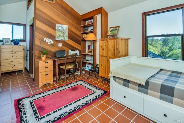 bedroom with tile patterned flooring, wood walls, and multiple windows