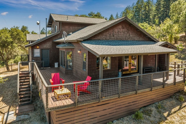 rear view of house with stairway, a deck, and a shingled roof