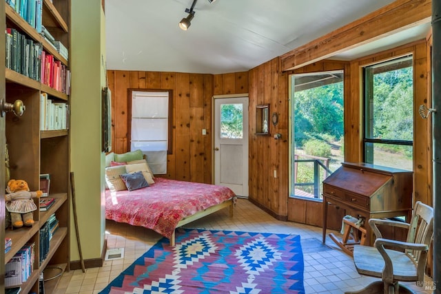 tiled bedroom featuring track lighting, wooden walls, and lofted ceiling