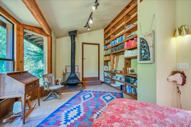 bedroom with track lighting, multiple windows, a wood stove, and lofted ceiling