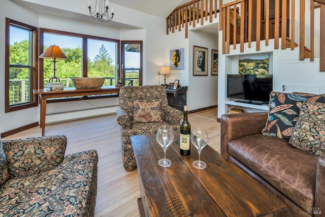 living area featuring baseboard heating, baseboards, an inviting chandelier, and hardwood / wood-style flooring