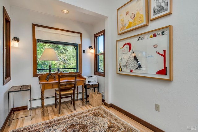 office featuring a wealth of natural light, baseboards, baseboard heating, and wood finished floors