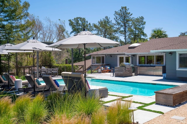 pool with grilling area and a patio