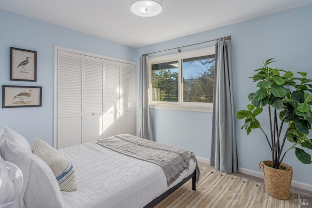 bedroom with a closet, light colored carpet, and baseboards