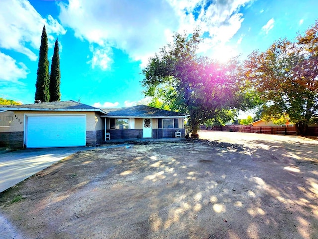 single story home with a garage, fence, stone siding, concrete driveway, and stucco siding