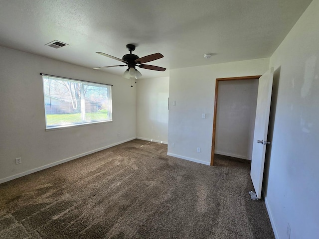 unfurnished bedroom with dark colored carpet, visible vents, a ceiling fan, a textured ceiling, and baseboards