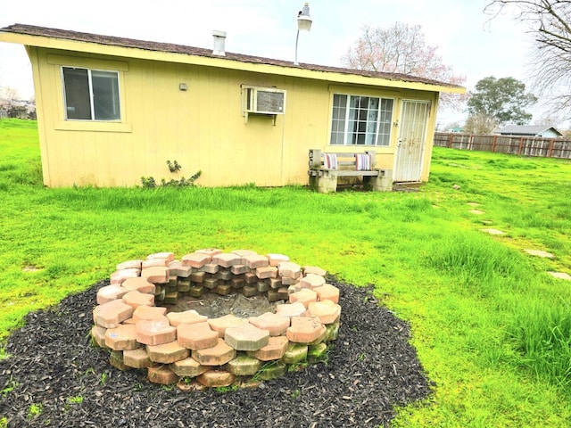 back of property with a yard, an outdoor fire pit, an outdoor structure, and fence