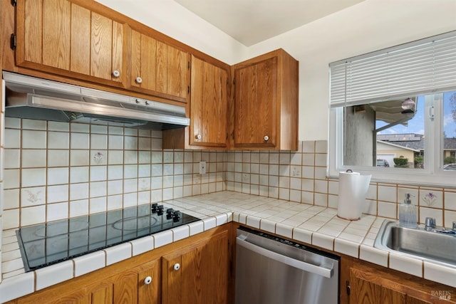 kitchen with tile countertops, black electric stovetop, under cabinet range hood, dishwasher, and brown cabinetry