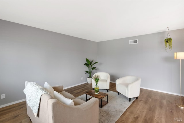 living room featuring visible vents, baseboards, and wood finished floors