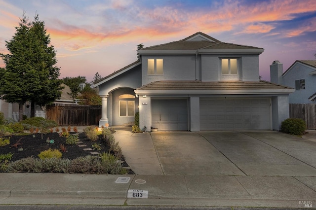 traditional-style home with a tile roof, stucco siding, concrete driveway, fence, and a garage