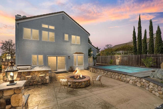 exterior space featuring a fire pit, outdoor dry bar, a fenced in pool, stucco siding, and a patio area