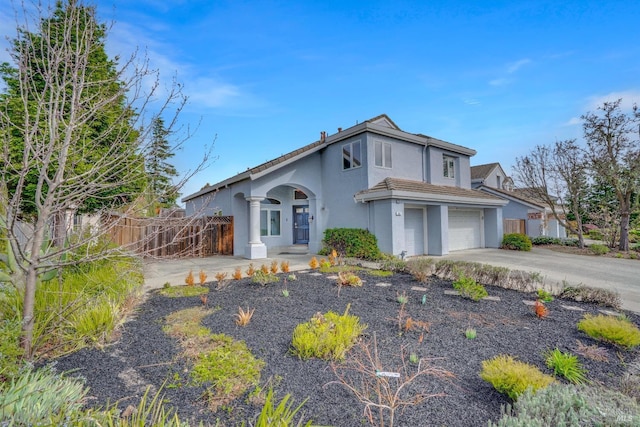 view of front of house with driveway, a garage, fence, and stucco siding