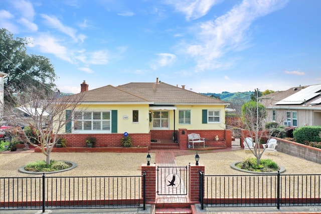 view of front of home featuring brick siding, a fenced front yard, a gate, and stucco siding