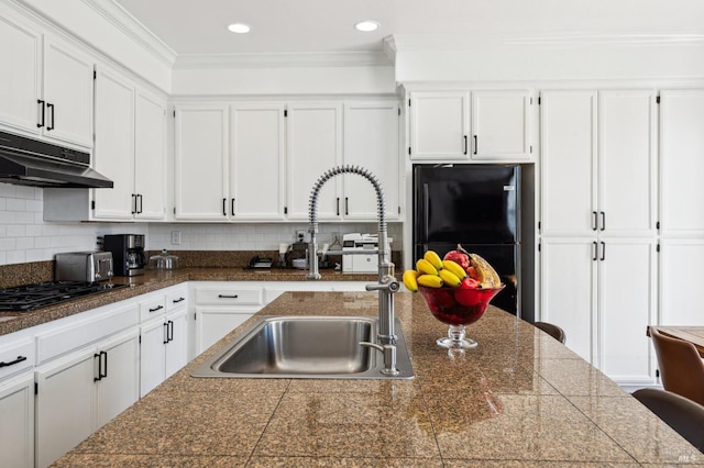 kitchen with tile countertops, under cabinet range hood, crown molding, black appliances, and a sink